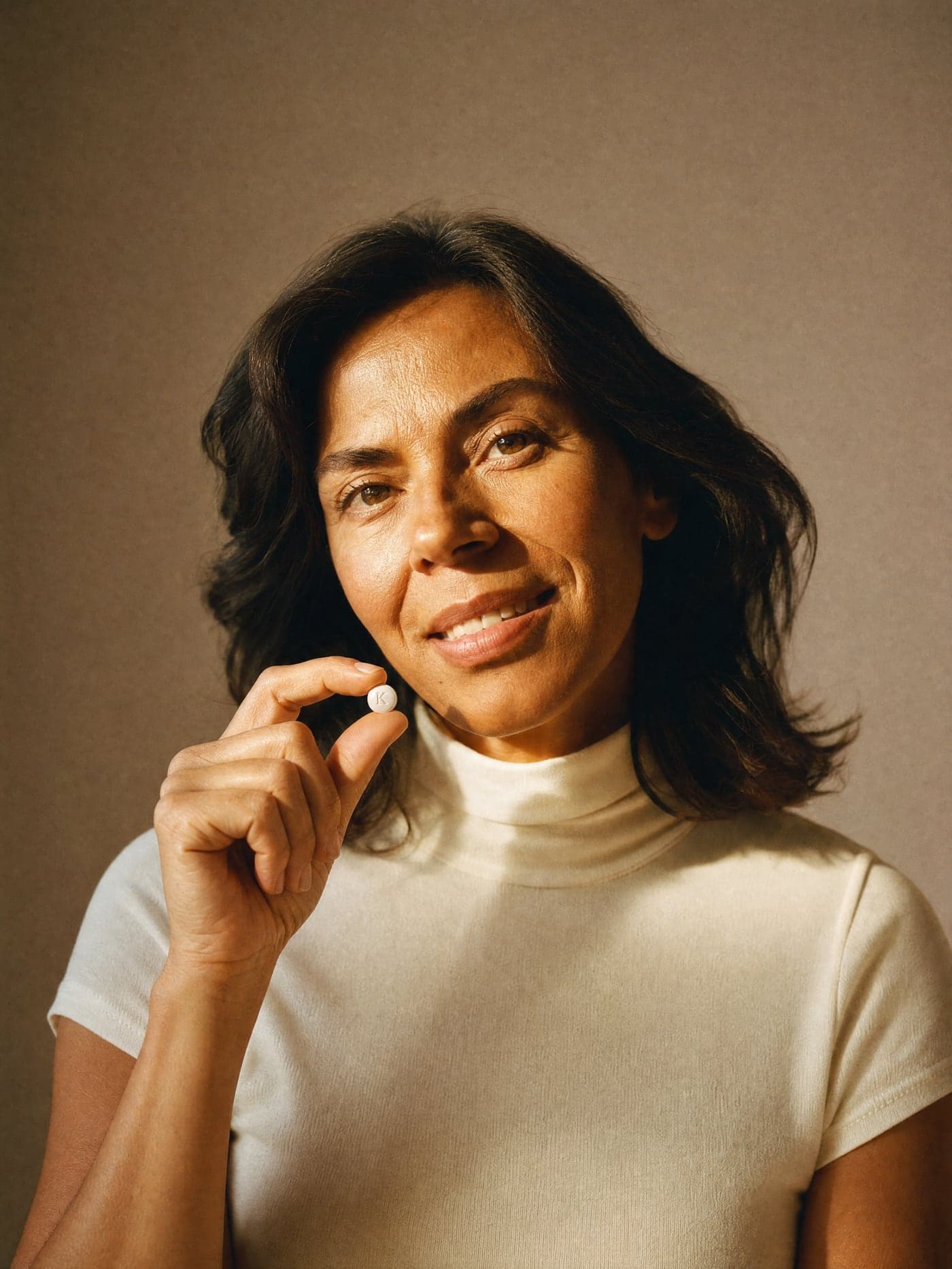 Woman in her 50s holding a Kina tablet, in soft window light